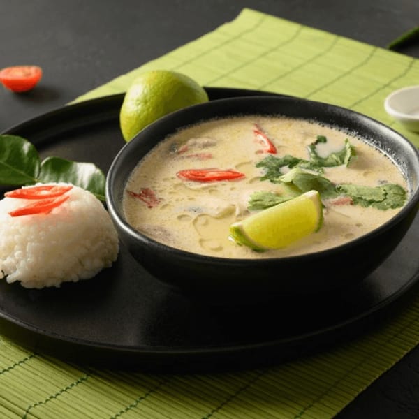 Creamy Tom Kha Gai soup with red chili, cilantro, and lime, served with rice.
